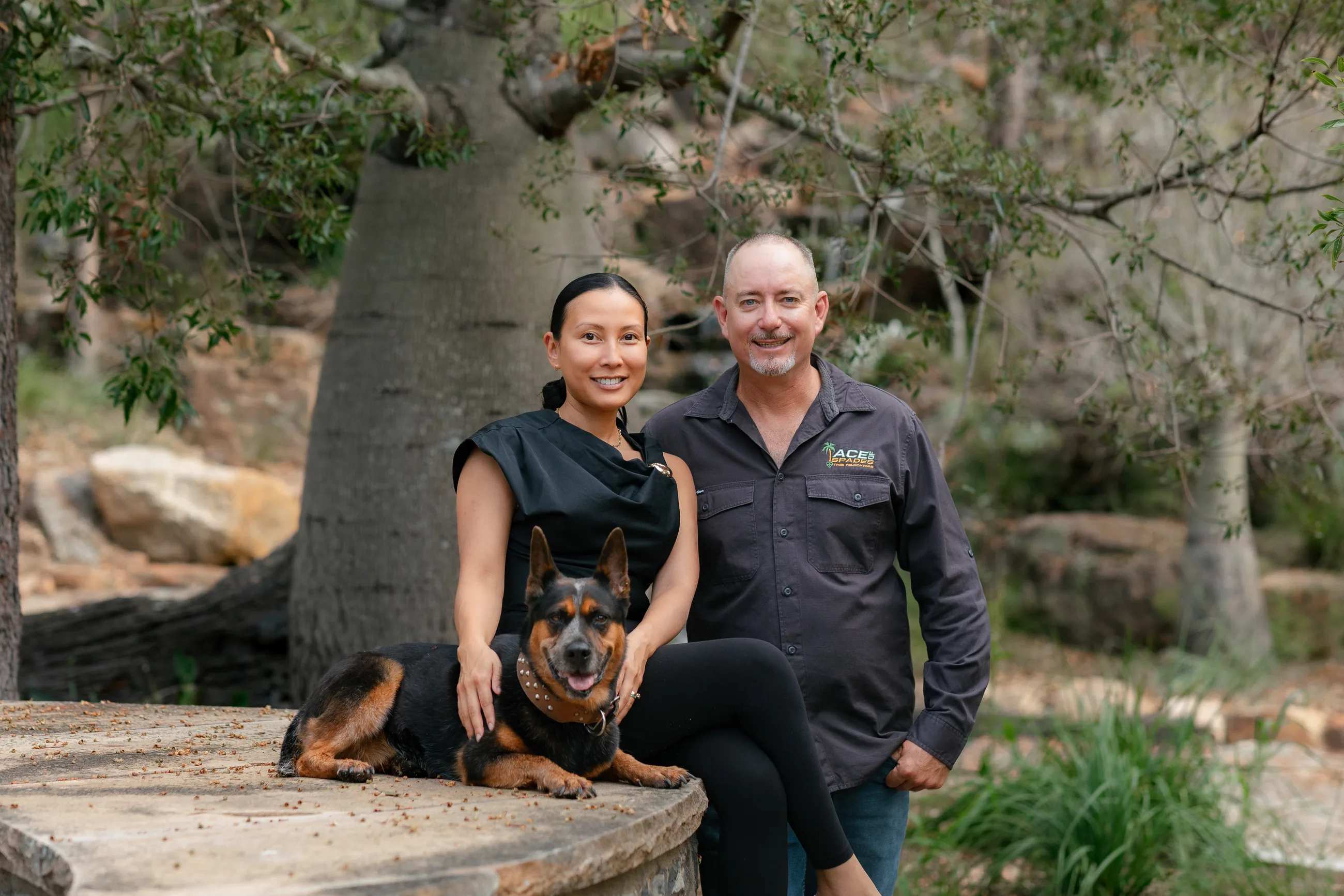 Russell and Aimee Clark with Ace the dog, sitting in front of a giant bottle tree